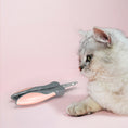 Load image into Gallery viewer, Cat lying down next to a closed pink and gray pet nail clipper on pink surface

