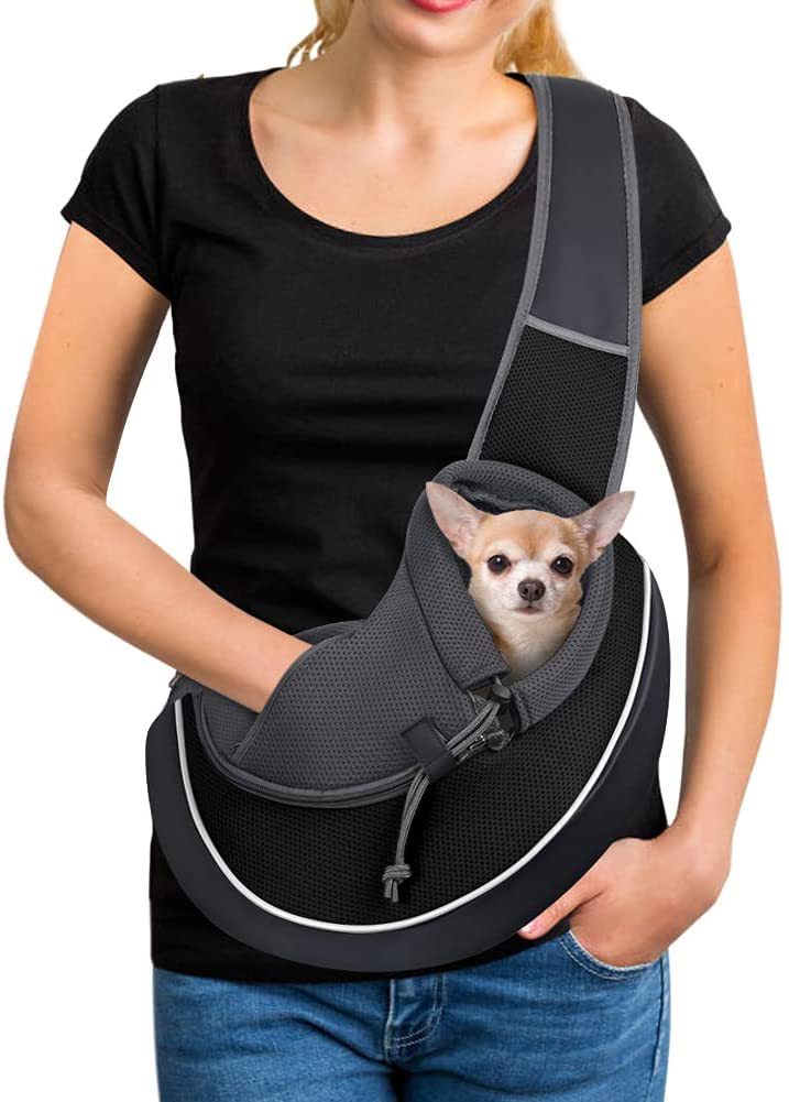 Smiling woman carrying a small chihuahua in black breathable mesh pet sling carrier