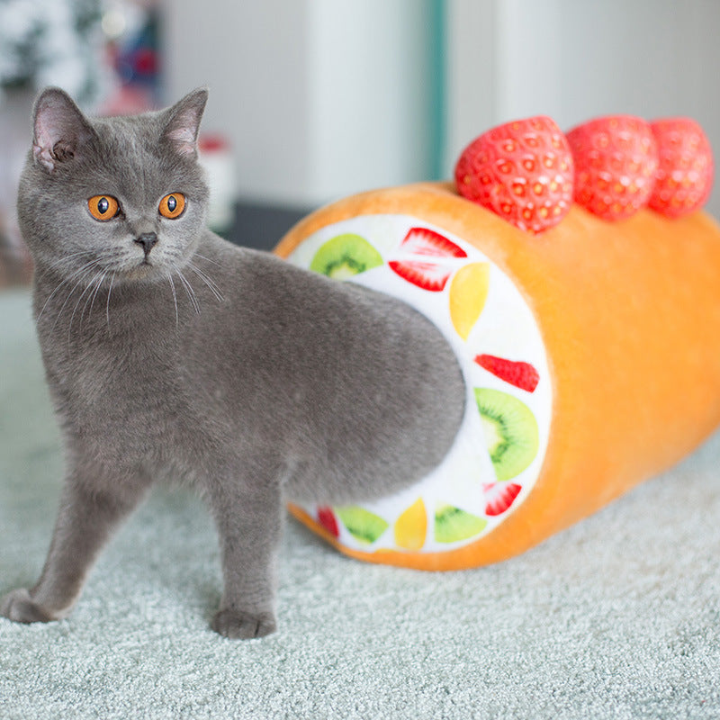 Gray cat partially stepping out from the colorful fruit patterned opening of the cake roll cat tunnel