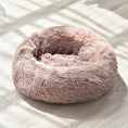 Load image into Gallery viewer, Light pink round plush pet bed in sunlight on wooden floor, showing fluffy material
