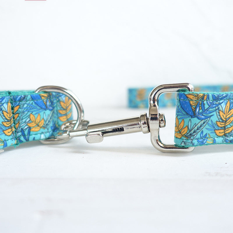 Close-up of silver metal clasp hooking onto metal D-ring of teal floral dog leash