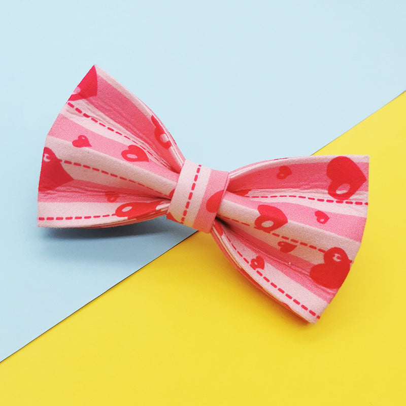 Pink heart patterned bowtie accessory for dog collar on blue and yellow background