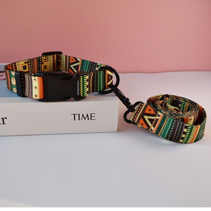 Green, orange, and black geometric patterned nylon dog collar and matching leash on white box with pink background