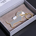 Load image into Gallery viewer, Metal dog keychain in gray enamel with gold-tone edges placed on soft gray pouch in gift box
