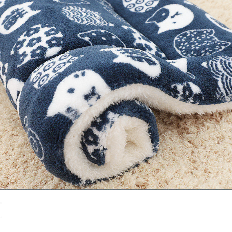 Rolled navy blue pet blanket featuring white owl and cat silhouettes with fleece backing