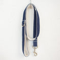 Load image into Gallery viewer, Full view of coiled denim leash hanging on white wall hook
