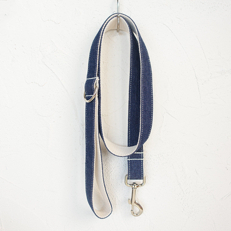 Full view of coiled denim leash hanging on white wall hook