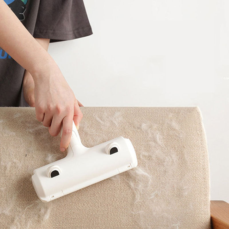 Person using white pet hair remover roller to remove hair from beige sofa