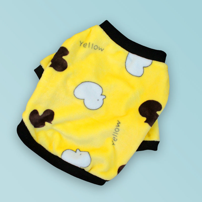 Flat lay of bright yellow fleece dog sweater with cartoon pattern and black ribbed collar and cuffs on blue background
