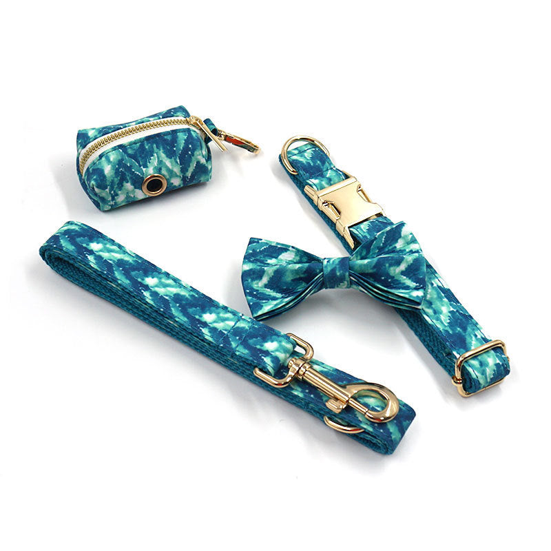 Blue tie-dye dog collar with gold buckle, matching leash, bow tie, and waste bag holder close-up