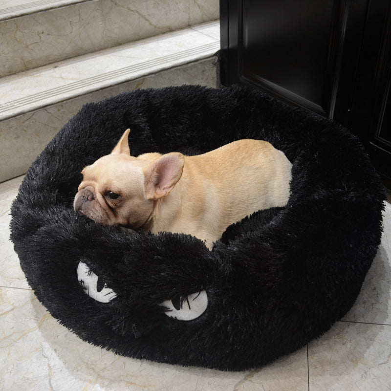Black plush round pet bed with a small dog resting, showing the fluffy texture and facial embroidery