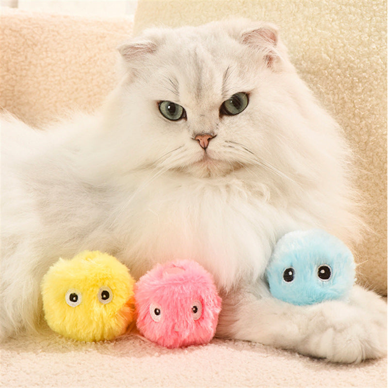 White fluffy cat resting with three colorful plush teaser balls in pink, yellow, and light blue