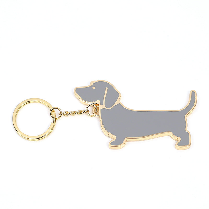 Metal dachshund dog keychain with gold-tone ring and gray enamel body on white background
