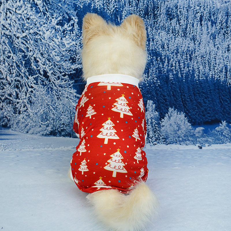 Small dog from behind showcasing red pajamas with white Christmas tree designs seated on a snowy winter scene