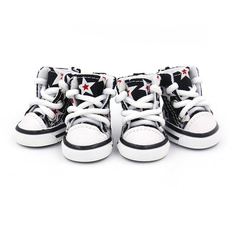 Four black and white star print high-top dog shoes with white laces showing front view