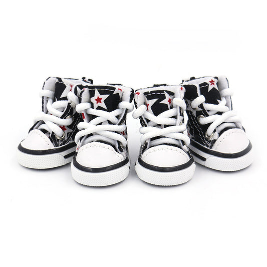 Four black and white star print high-top dog shoes with white laces showing front view