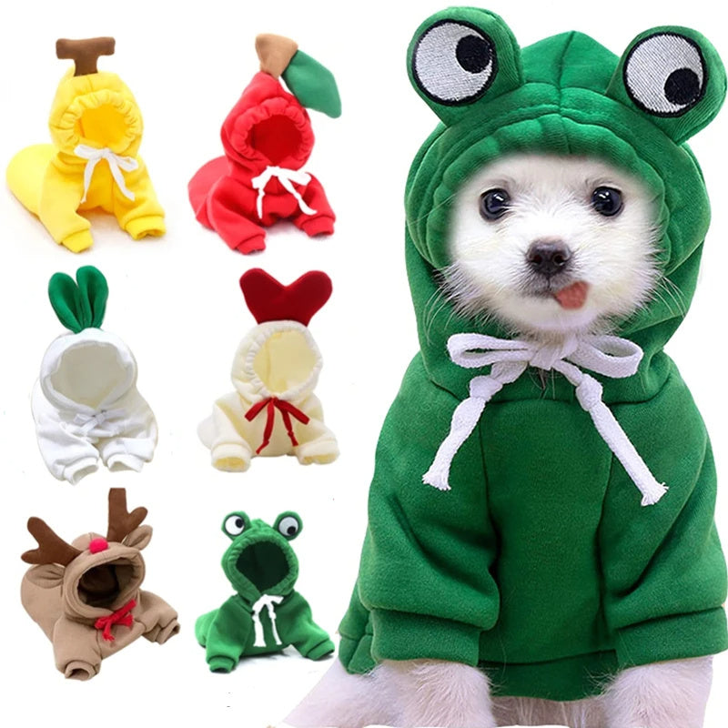 Collection of small dog hoodies with playful fruit and animal designs in various colors including green frog, orange carrot, red apple, white radish, and brown reindeer