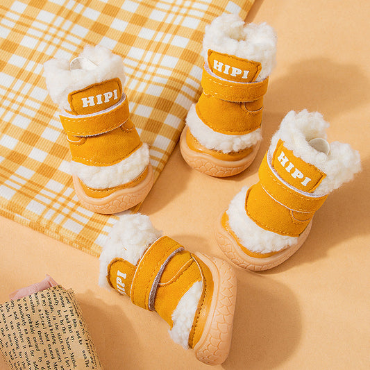 Four mustard yellow winter dog booties with white fleece lining and rubber soles arranged on a yellow checkered cloth