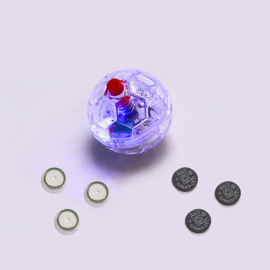 Close-up of clear glowing plastic cat toy ball with red button and included batteries displayed