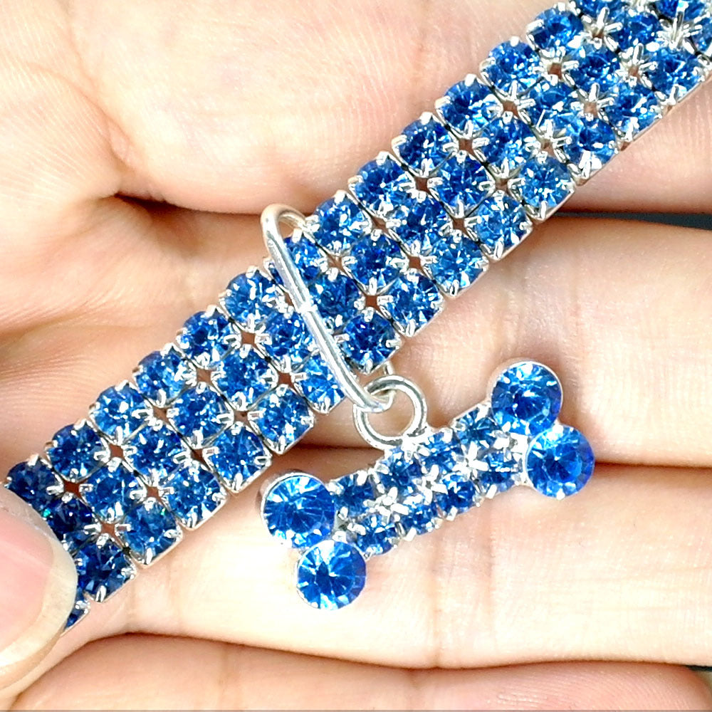 Close-up of blue rhinestone dog collar with matching crystal bone charm held in hand