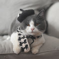 Load image into Gallery viewer, Gray and white cat wearing a black knitted beret and black-beige plaid scarf lying on a gray cushion
