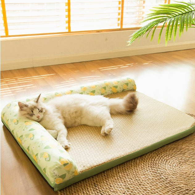 White cat resting comfortably on a cooling bolster pet bed with woven straw-like mat and lemon pattern bolsters.