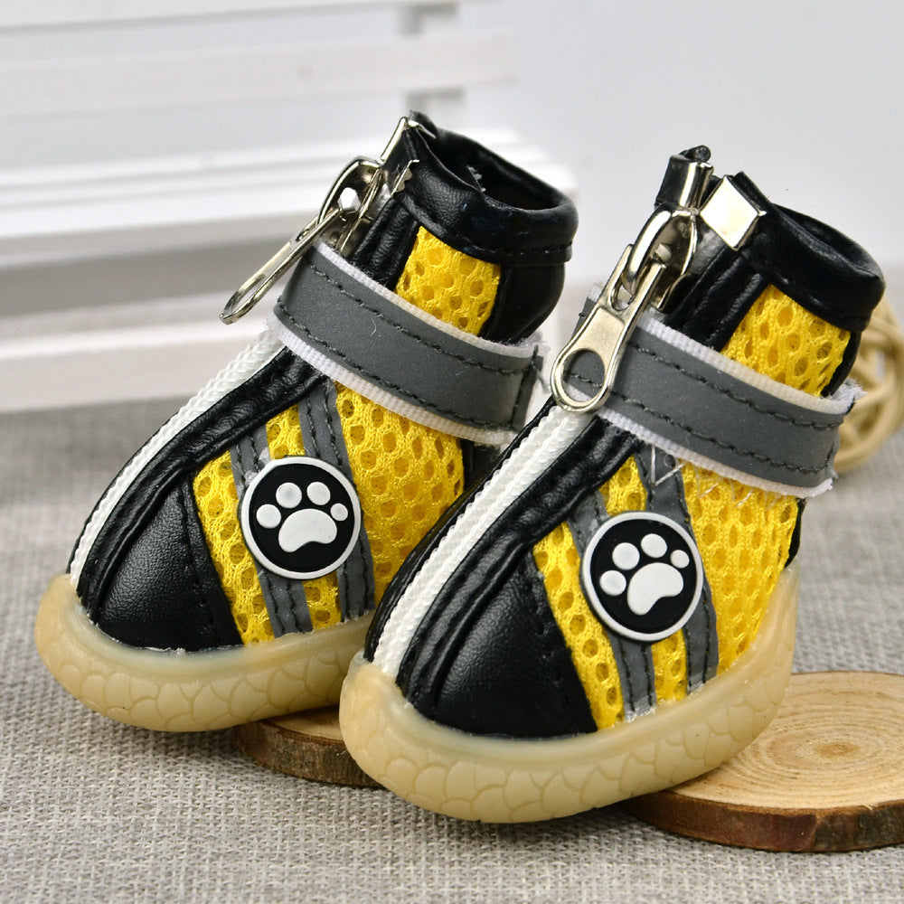 Yellow breathable dog boots standing side by side on wooden coasters, showing padded collar and sole texture