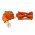 Load image into Gallery viewer, Rolled orange dog leash and orange bow tie on white surface
