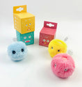 Load image into Gallery viewer, Three plush cat teaser balls in yellow, pink, and blue next to their colorful cartoon-themed packaging against a white background
