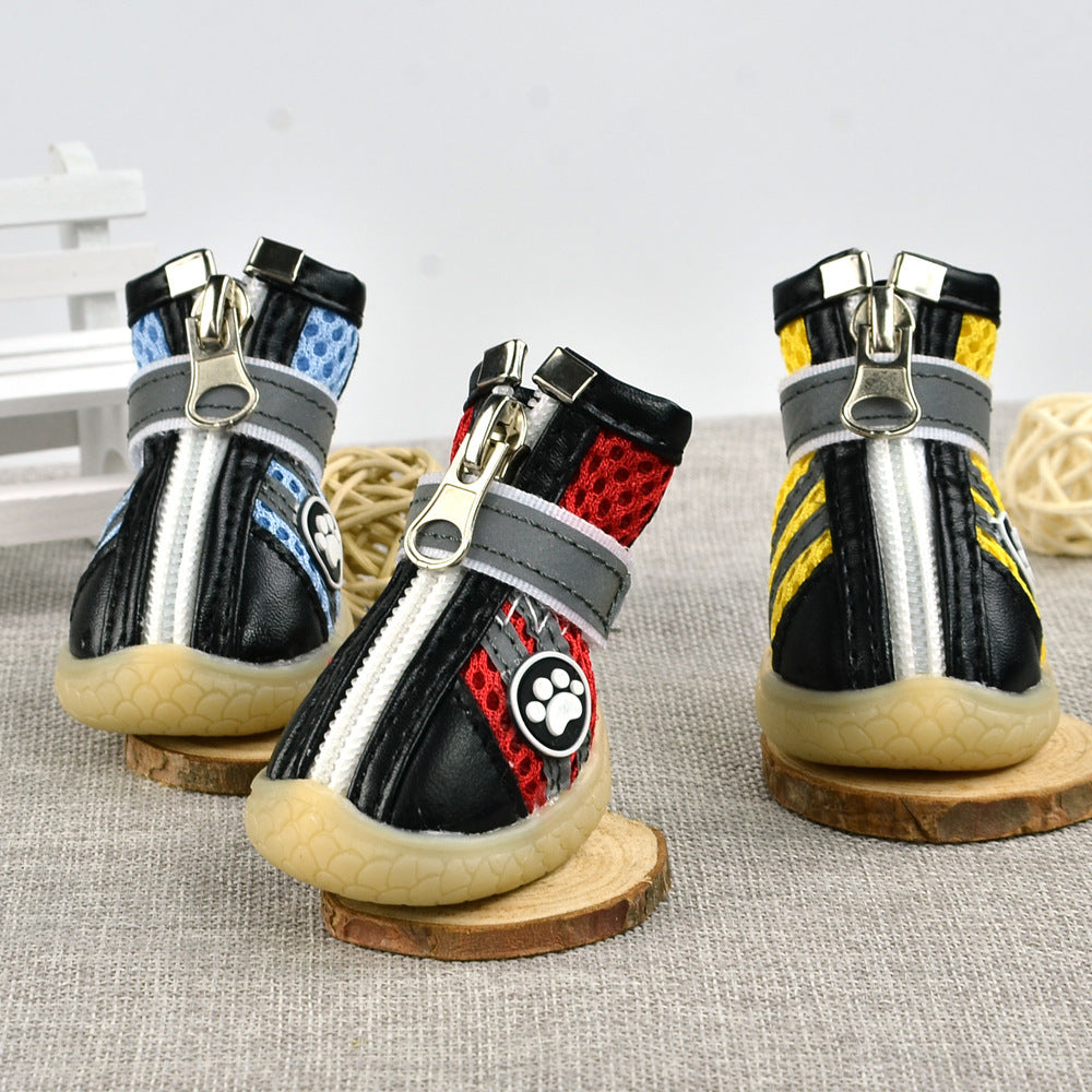 Three breathable reflective dog boots in blue, red, and yellow colors displayed upright on wooden coasters