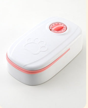Single white automatic pet feeder with pink mechanical timer dial and paw-print embossed cover on white background