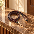 Cargar la imagen en la vista de la galería, Red dog leash with dark centre, coloured stitching and rose-gold clasp on brown marble
