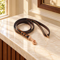 Load image into Gallery viewer, tan leash with rose-gold hardware on light ivory-beige marble
