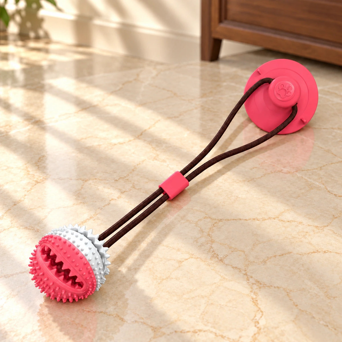 White and pink textured dog tug ball with pink suction cup on light ivory-beige marble