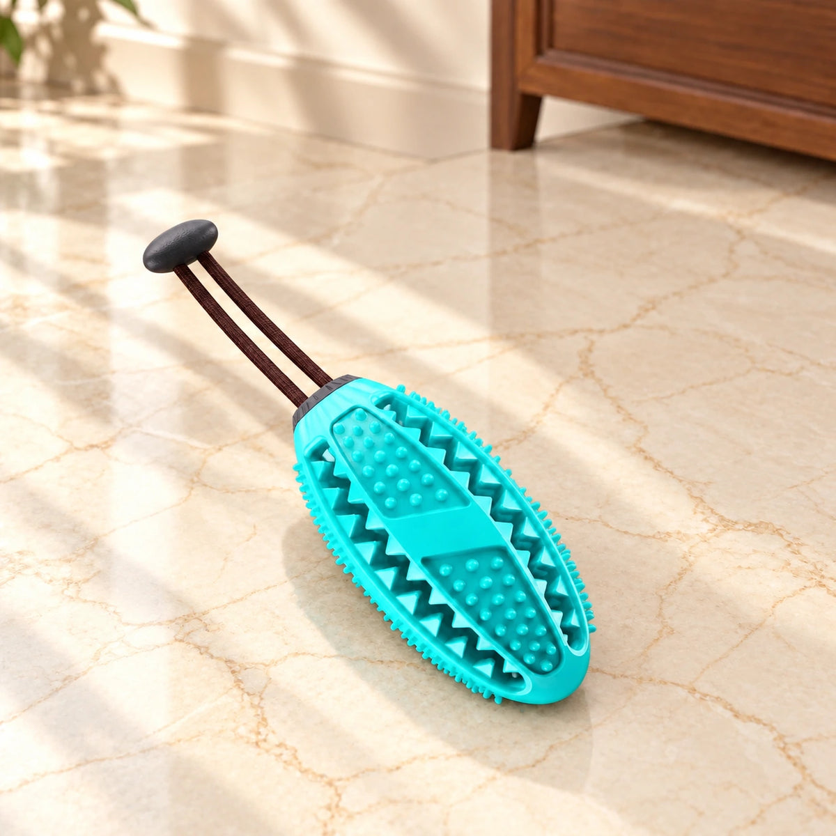 Turquoise oval dog chew toy with short dark pullcord on light ivory-beige marble