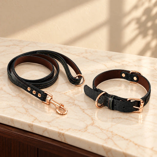 Black croc-texture dog collar and matching leash with rose-gold hardware on light ivory-beige marble.