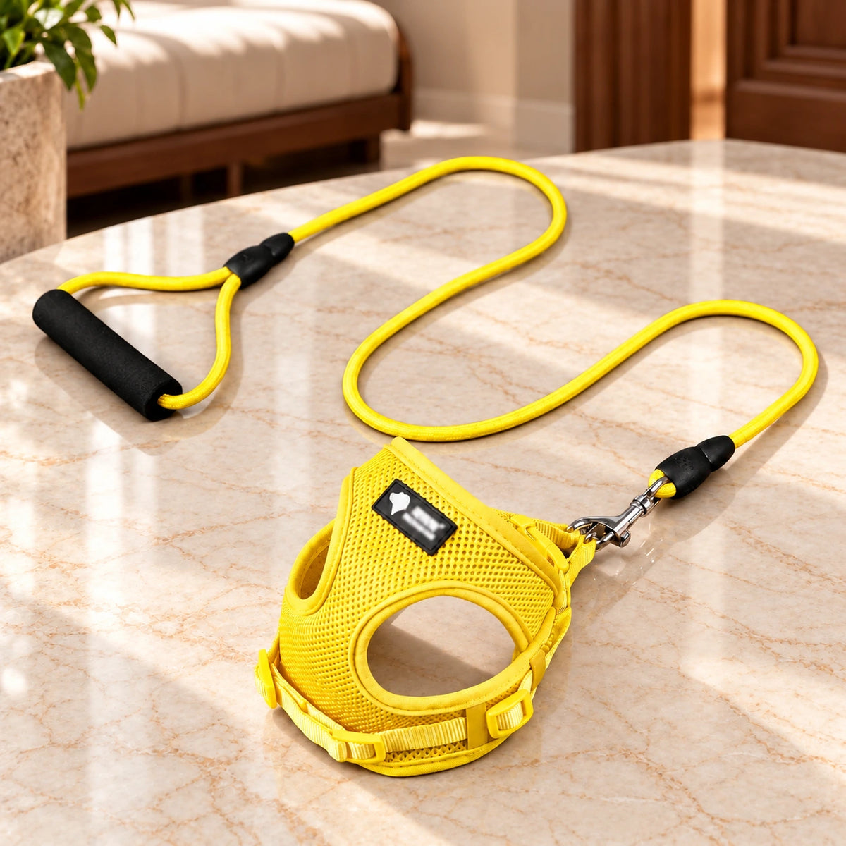 Yellow mesh dog harness and matching rope leash with black foam handle on light ivory-beige marble