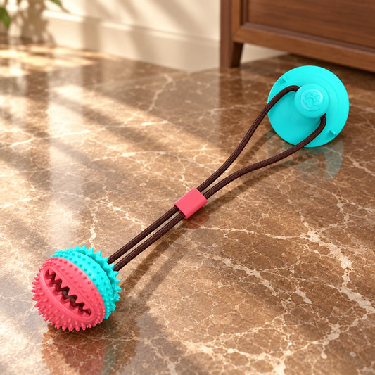 Turquoise and coral suction-cup tug ball dog toy with connecting rope on brown marble.