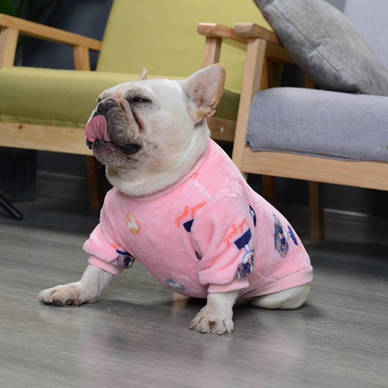 French bulldog in pink plush animal print sweater sitting on gray floor with tongue out