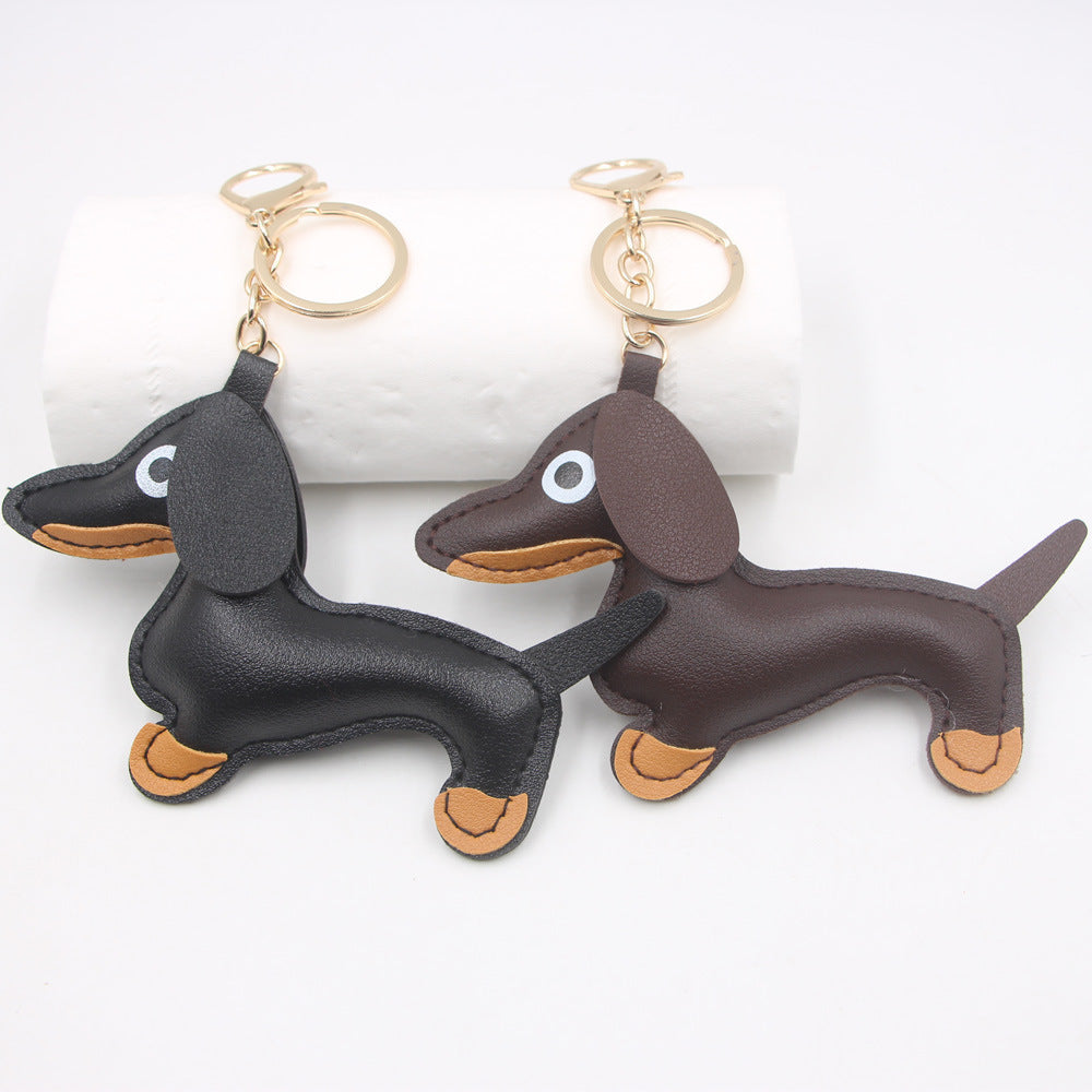 Two sausage dog keychains side-by-side in black and brown faux leather on a white surface