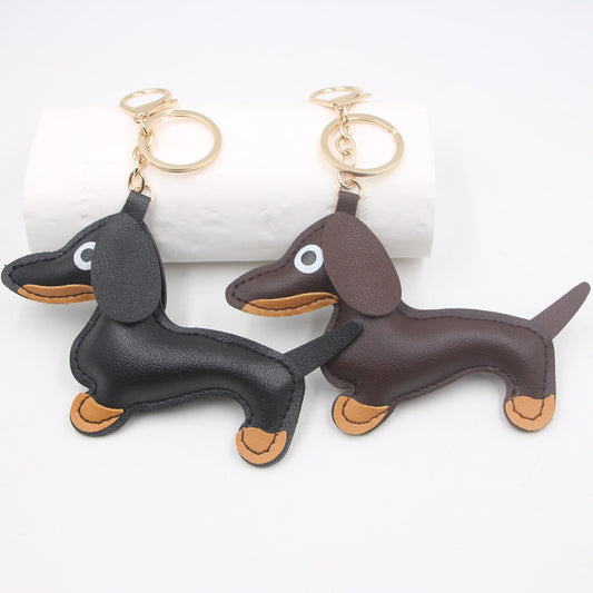 Two sausage dog keychains side-by-side in black and brown faux leather on a white surface