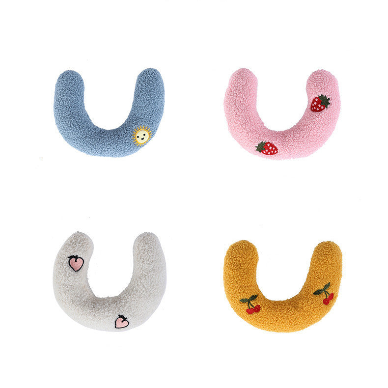Four U-shaped plush pet pillows in blue, pink, white, and yellow each with unique embroidered patterns