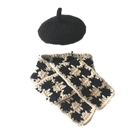 Black knitted beret and black-beige plaid knitted scarf laid flat on a white background