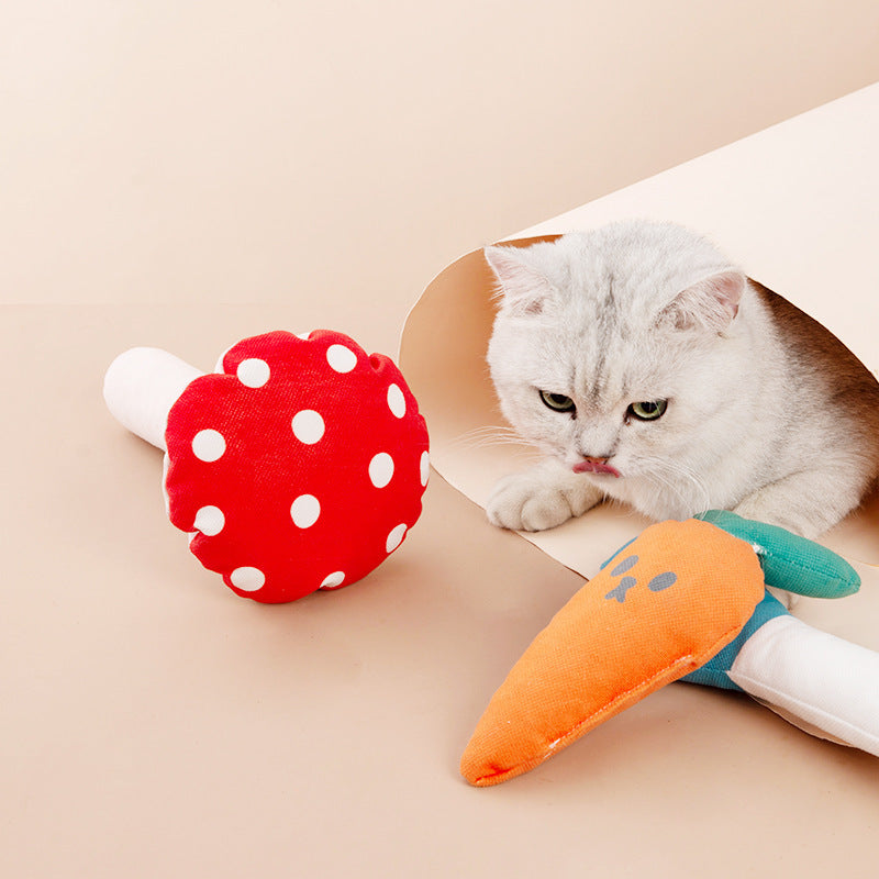 Cat playing with red polka dot mushroom and orange carrot plush toys