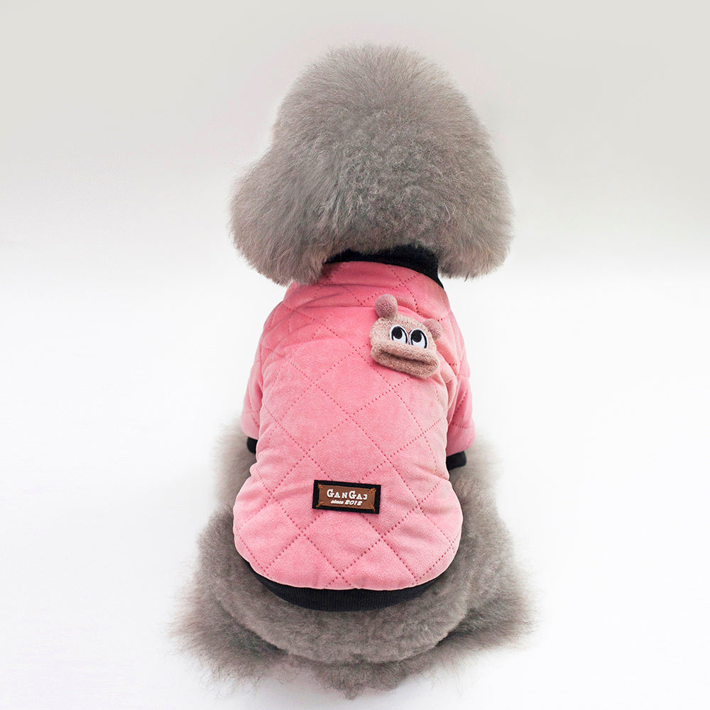 Gray fluffy dog seen from back wearing soft pink quilted jacket with black knit collar and cute animal patch