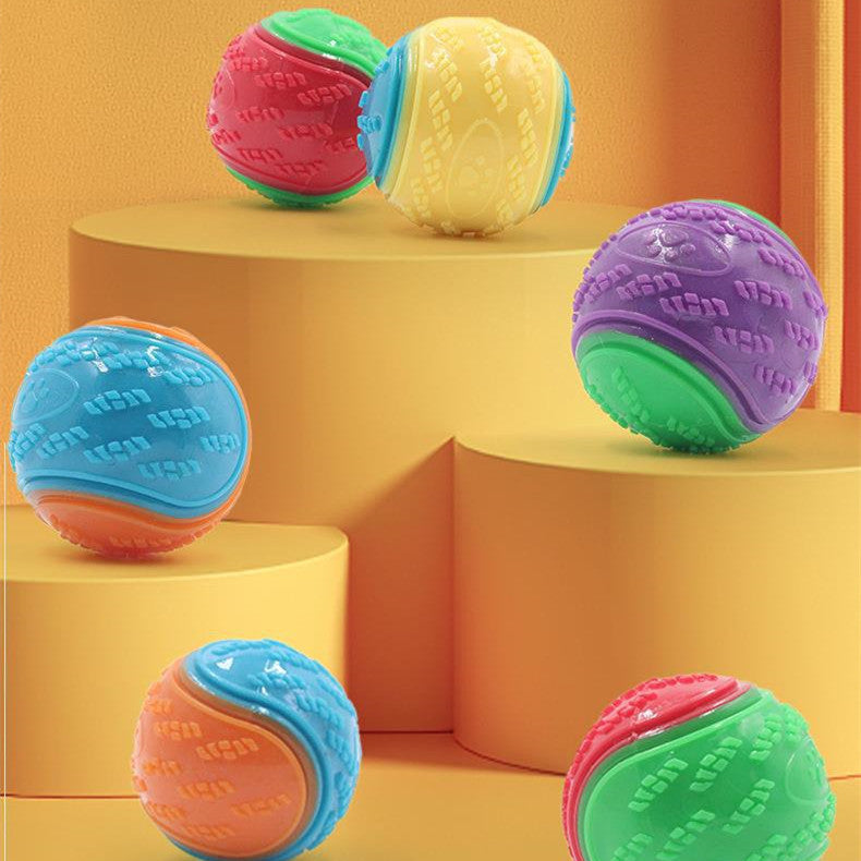 Group of colorful bite-resistant rubber dog toy balls displayed on yellow steps with an orange background