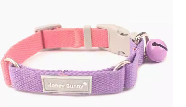 Close-up side view of pink and purple woven dog collar with plastic release buckle and attached bell
