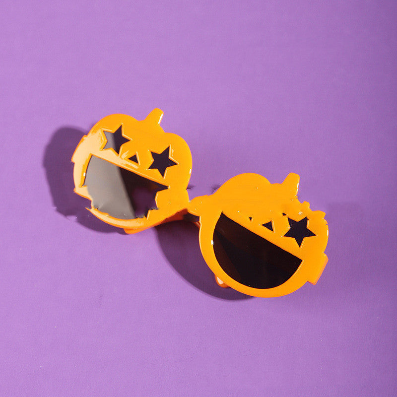 Orange pumpkin-shaped sunglasses on purple background showing star cutouts on lenses