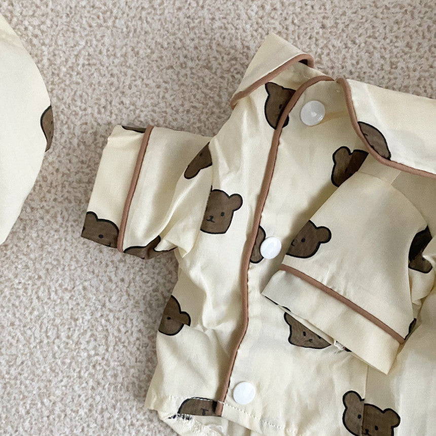 Close-up of front snap buttons and brown piping detail on pet's beige cotton pajama shirt