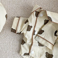 Load image into Gallery viewer, Close-up of front snap buttons and brown piping detail on pet's beige cotton pajama shirt
